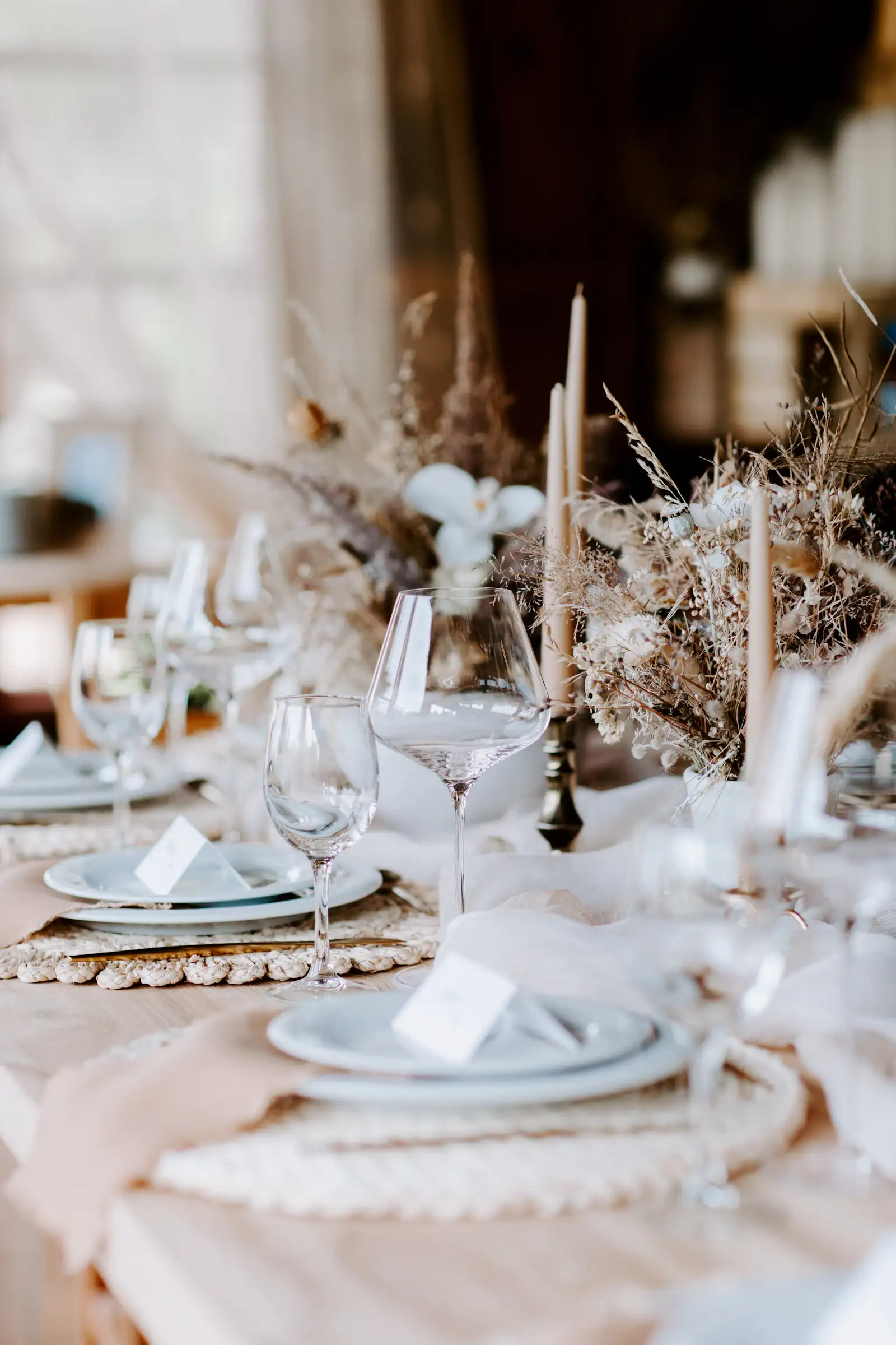 Candlelit event table dressed with dried florals, glassware and place cards
